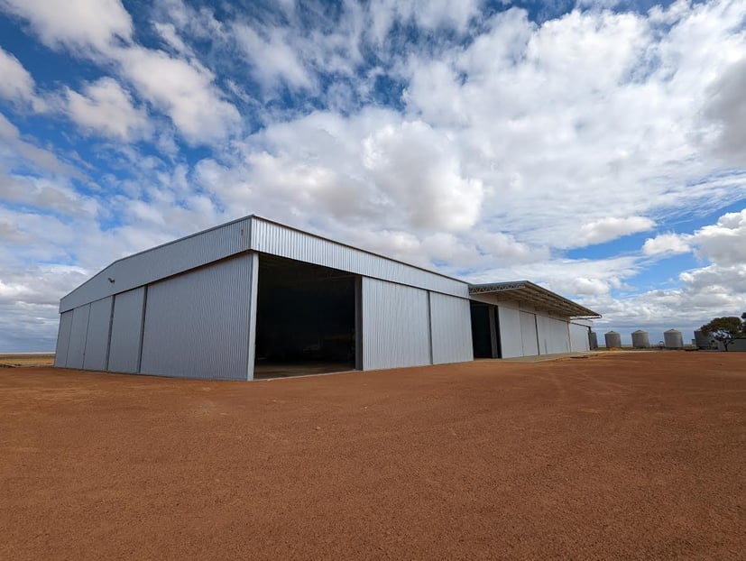 Large machinery shed in red sand lot