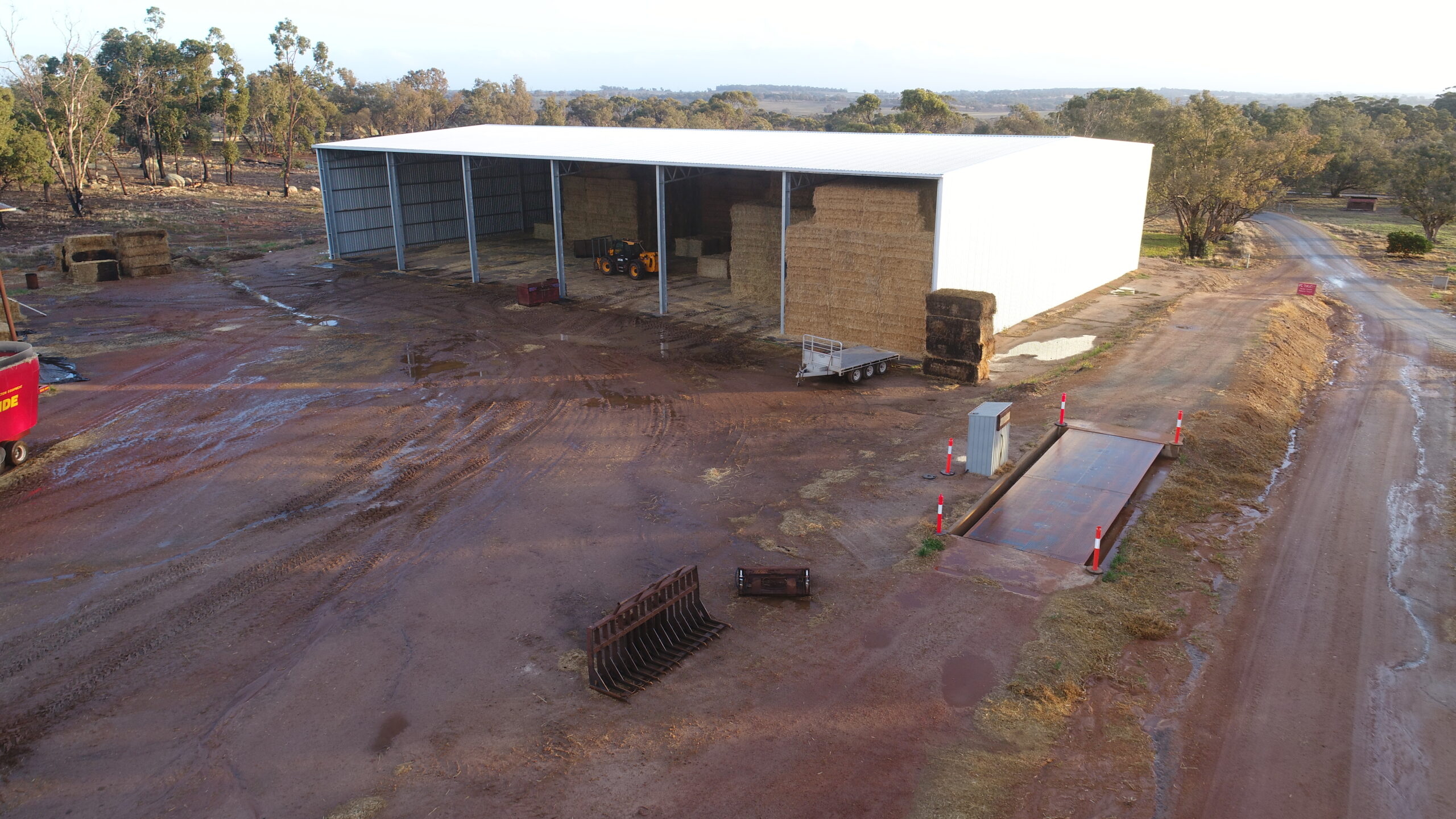 Aerial view of large steel hay shed with machinery and bales