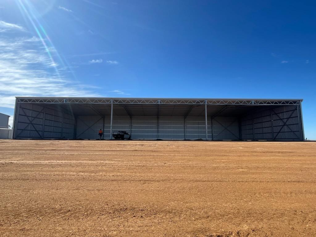 Large empty farm shed on dirt lot with man inside